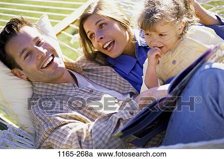 Stock Image - people, relaxation, smiling, reading, hammock, book, outdoors. Fotosearch