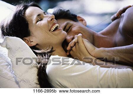 Stock Image - people, smiling, couple, bed, laughing, playful. Fotosearch