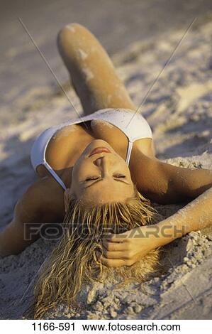 Stock Image - people, woman, beach, blond, posing, wet, lying down. Fotosearch