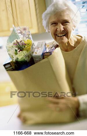 Stock Photo - people, woman, smiling, senior, holding, bag, carrying. Fotosearch