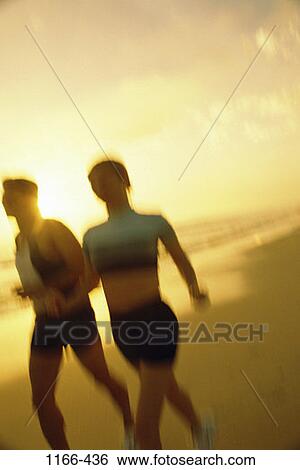 Stock Photograph - sand, people, blur, water, running, sunset, beach. Fotosearch