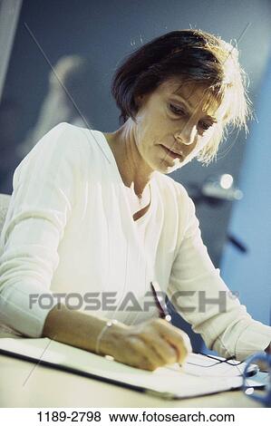 desk, woman, concentrating, business, Middle-aged, writing, serious View Large Photo Image Stock Photo - desk, woman, concentrating, business, Middle-aged, writing, serious. Fotosearch