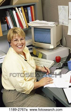 Stock Image - desk, woman, smiling, computer, business, Middle-aged, smile. Fotosearch