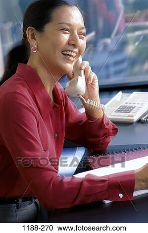 Stock Image - desk, woman, telephone, talking, Asian, phone, business. Fotosearch