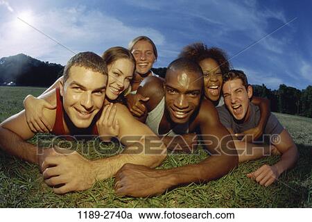 Stock Image - grass, multiethnic, people, smiling, happy, laughing. Fotosearch