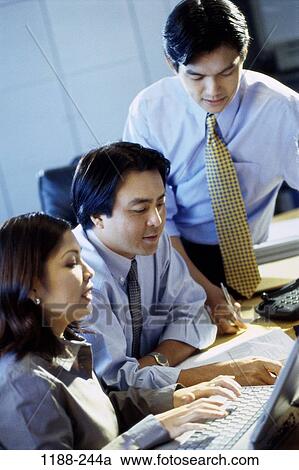 Stock Image - groups, Asian, papers, typing, shirtsleeves, leaning, business. Fotosearch