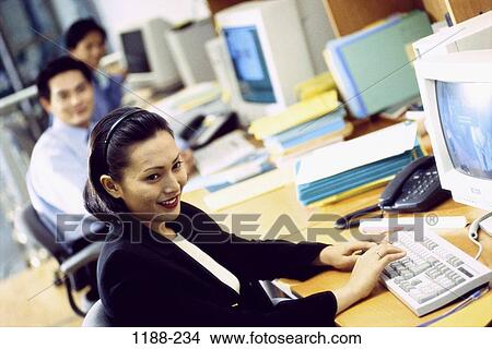 Picture - groups, people, desk, smiling, Asian, phone, typing. Fotosearch