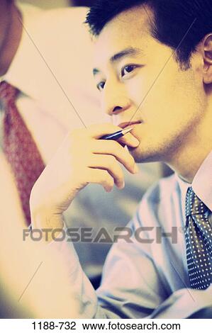 Stock Image - meeting, pen, Asian, listening, business, teamwork, contemplation. Fotosearch