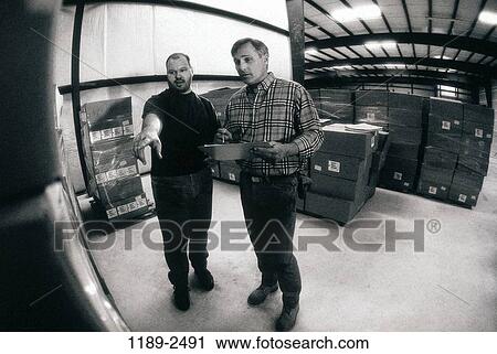 Stock Image - men, people, talking, pointing, point, Middle-aged, warehouse. Fotosearch