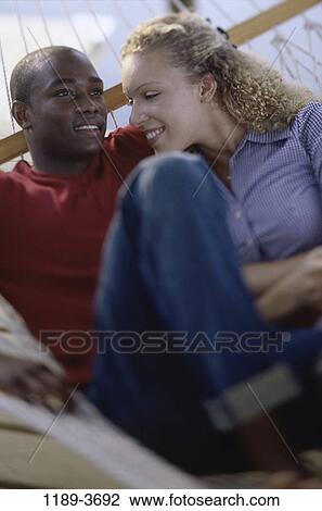 Stock Image - multiethnic, people, couple, hammock, outdoors, lying, lie. Fotosearch