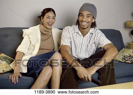 Stock Image - multiethnic, people, couple, laughing, entertainment, television. Fotosearch