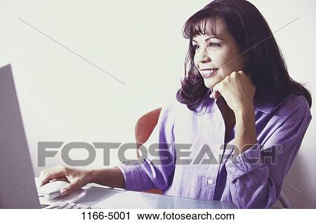 Stock Image - people, home, woman, smiling, technology, sitting. Fotosearch