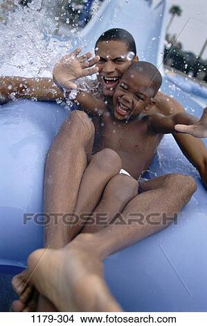 Picture - people, laughing, splash, sliding, inner tube, outdoors, adventurous. Fotosearch