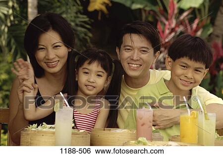 Stock Photograph - people, smiling, table, Asian, sitting, holding. Fotosearch