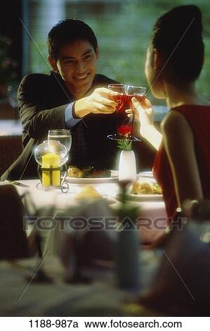 Stock Image - people, table, Asian, couple, toasting, wine, drinking. Fotosearch