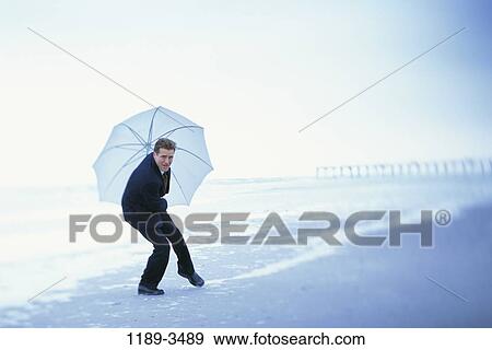 people, umbrella, windy, wind, beach, stress View Large Photo Image Stock Photo - people, umbrella, windy, wind, beach, stress. Fotosearch