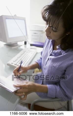 Stock Photograph - people, woman, Hispanic, computer, Middle-aged, writing, finance. Fotosearch