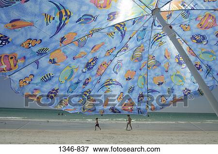 Close-up of a beach umbrella with children running in the background View Large Photo Image Stock Photo - Close-up of a beach umbrella with children running in the background. Fotosearch