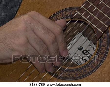 Close-up of a person's hand playing a guitar View Large Photo Image Stock Photo - Close-up of a person's hand playing a guitar. Fotosearch