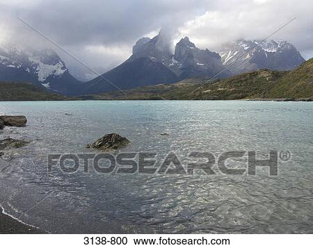 Stock Image - Clouds over a lake with mountains in the background, Lake Pehoe, Cuernos Del Paine, Torres del Paine National Park, Patagonia, Chile. Fotosearch