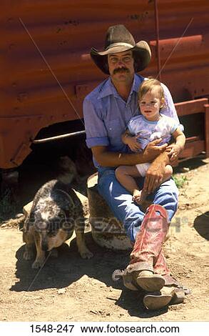 Cowboy carrying his daughter and a dog sitting beside them View Large Photo Image Stock Photo - Cowboy carrying his daughter and a dog sitting beside them. Fotosearch