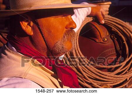 Stock Photo - Cowboy next to horse with lasso rope. Fotosearch