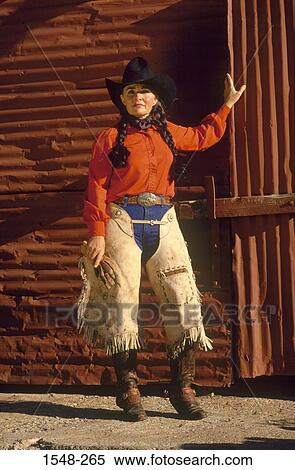 Cowgirl with hat and chaps standing outside a barn View Large Photo Image Stock Photography - Cowgirl with hat and chaps standing outside a barn. Fotosearch