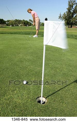 Golf flag in a hole with a woman in the background View Large Photo Image Stock Photography - Golf flag in a hole with a woman in the background. Fotosearch