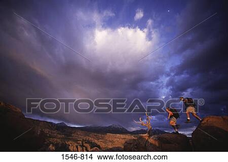 Low angle view of a couple hiking at sunset, Moab, Utah, USA View Large Photo Image Picture - Low angle view of a couple hiking at sunset, Moab, Utah, USA. Fotosearch