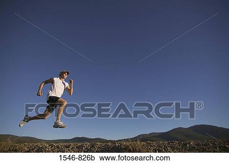 Low angle view of a man running in a field View Large Photo Image Stock Image - Low angle view of a man running in a field. Fotosearch
