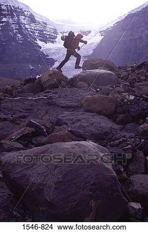 Side profile of a mountaineer jumping from rock to rock, Alberta, Canada View Large Photo Image Picture - Side profile of a mountaineer jumping from rock to rock, Alberta, Canada. Fotosearch