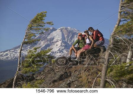 Stock Photograph - Three hikers resting on a rock, Mt Adams, Washington State, USA. Fotosearch