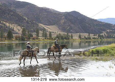 Two cowboys crossing river on horses, Montana, USA View Large Photo Image Stock Photo - Two cowboys crossing river on horses, Montana, USA. Fotosearch