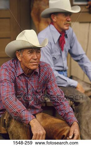Two cowboys sitting by a barn View Large Photo Image Stock Photo - Two cowboys sitting by a barn. Fotosearch