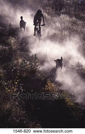 Woman mountain biking on a dusty trail with two dogs, California, USA View Large Photo Image Stock Image - Woman mountain biking on a dusty trail with two dogs, California, USA. Fotosearch