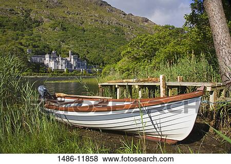 Stock Photo - Boat at the lakeside with an abbey in the background, Kylemore Abbey, Lake Kylemore, Connemara, County Galway, Connacht Province, Republic of Ireland. Fotosearch