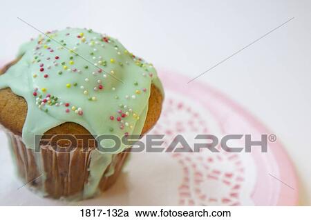 Stock Image - Close-up of an iced muffin on a paper plate. Fotosearch