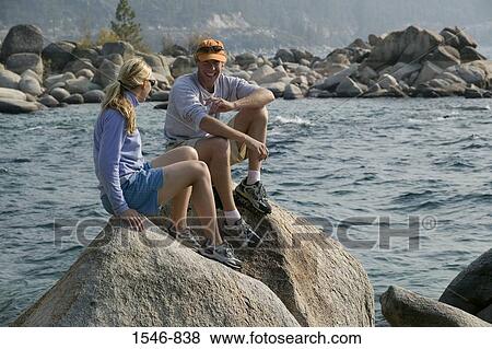 Couple sitting on a rock at the lakeside, Lake Tahoe, California, USA View Large Photo Image Stock Photo - Couple sitting on a rock at the lakeside, Lake Tahoe, California, USA. Fotosearch