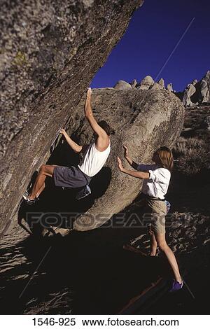 Man climbing a rock with a woman standing behind him for support, The Buttermilks, California, USA View Large Photo Image Stock Photography - Man climbing a rock with a woman standing behind him for support, The Buttermilks, California, USA. Fotosearch