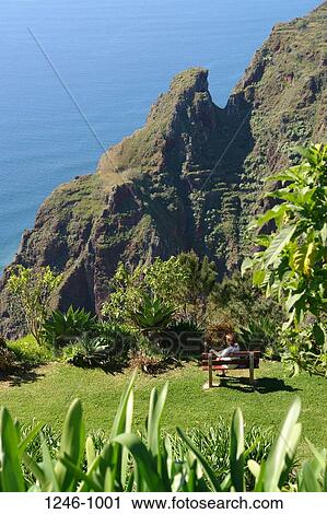 Person sitting on bench at the coast, Prazeres, Madeira, Portugal View Large Photo Image Stock Image - Person sitting on bench at the coast, Prazeres, Madeira, Portugal. Fotosearch