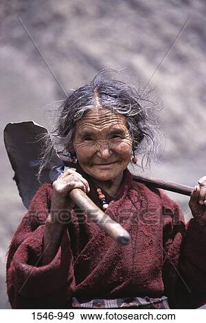 Stock Photo - Portrait of a senior woman with a shovel on her shoulder, Samagaon Village, Nepal. Fotosearch