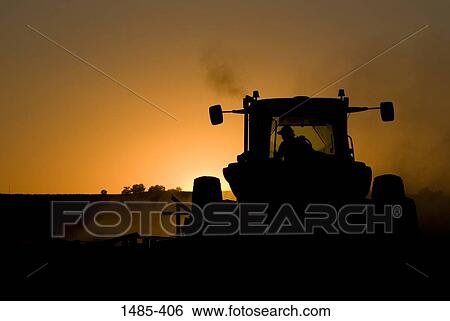 Stock Photograph - Silhouette of a farmer plowing a field with a tractor. Fotosearch