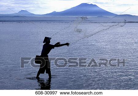 Stock Photo - Silhouette of a fisherman throwing a fishing net in the sea, Sanur Beach, Bali, Indonesia. Fotosearch