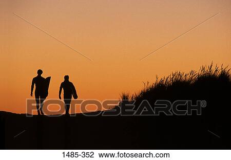 Silhouette of two people walking with surfboards on the beach View Large Photo Image Stock Image - Silhouette of two people walking with surfboards on the beach. Fotosearch