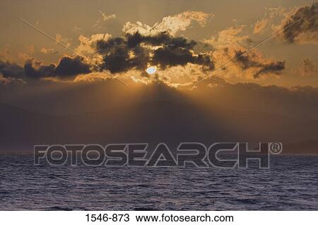 Stock Image - Sunlight streaming through clouds over the lake, Lake Tahoe, Nevada, USA. Fotosearch