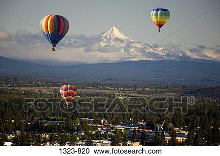 Three hot air balloons floating over a city with mountains in the background, Mt Jefferson, Bend, Oregon, USA View Large Photo Image Stock Image - Three hot air balloons floating over a city with mountains in the background, Mt Jefferson, Bend, Oregon, USA. Fotosearch