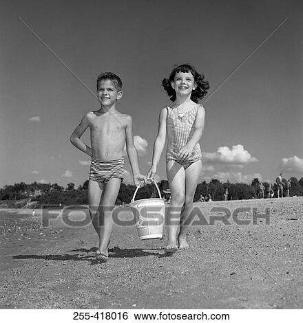 Boy and girl carrying bucket on beach View Large Photo Image Stock Photograph - Boy and girl carrying bucket on beach. Fotosearch