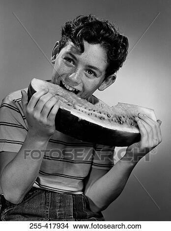 Picture - Boy eating large portion of water melon. Fotosearch