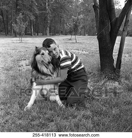 Stock Image - Boy embracing dog on grass. Fotosearch