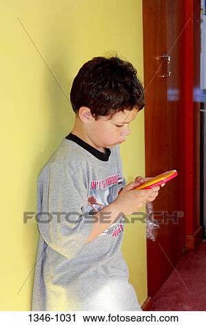 Boy playing with a handheld video game View Large Photo Image Stock Image - Boy playing with a handheld video game. Fotosearch